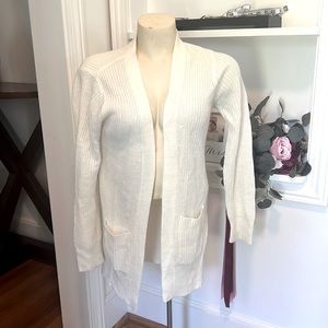 Small off white knit sweater with pockets. The brand name Ambiance.